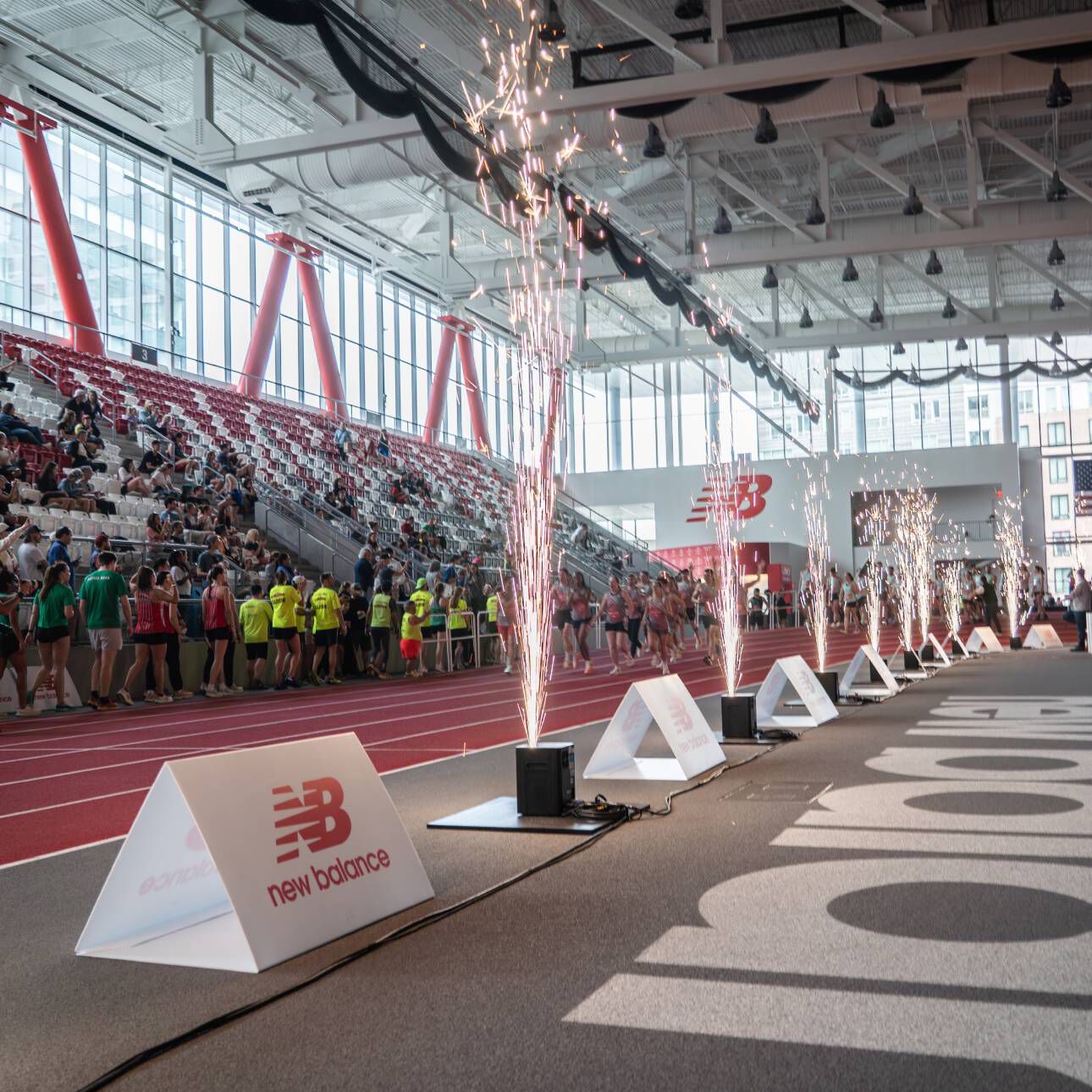 A New Balance event at the track with fireworks going off and people sitting in bleachers